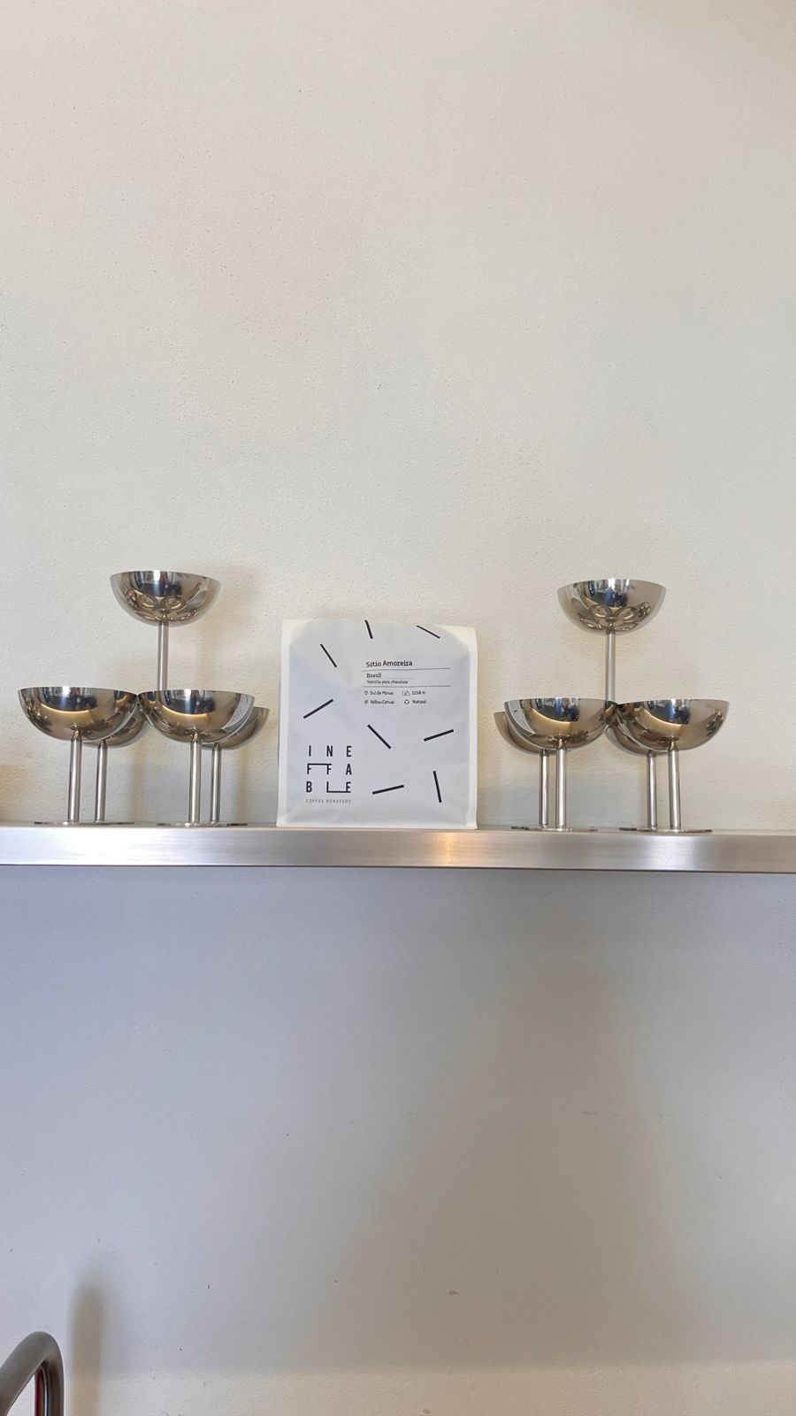 NŌMA specialty coffee shelf with cups and a coffee bag at the Tavira flagship